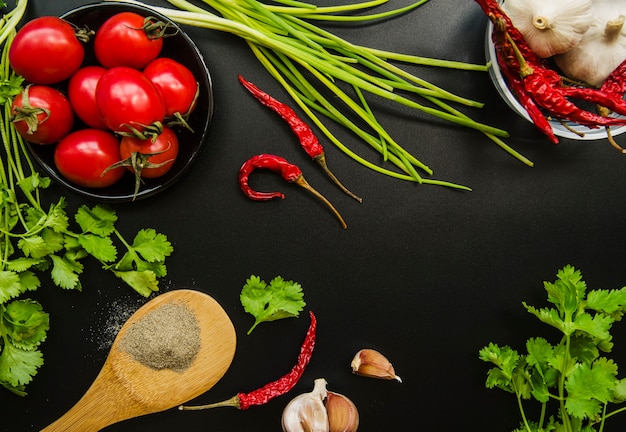 Verhoogde weergave van tomaat; rode pepers; lente-ui; knoflook; peterselie en kruiden op zwarte achtergrond