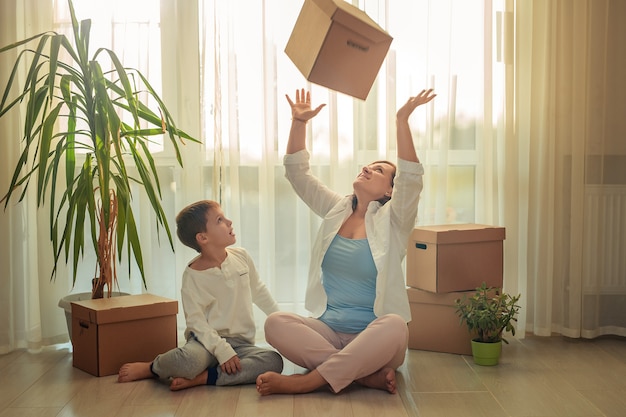 Verhuizen naar een nieuw huis. gelukkige moeder en zoon sorteerboxen