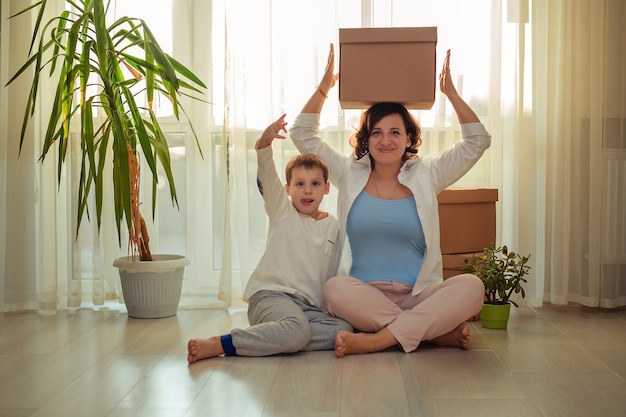 Verhuizen naar een nieuw huisgezin, moeder en zoon met kartonnen dozen