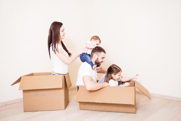 Verhuizen naar het nieuwe huis, familie spelen met kartonnen dozen in lege kamer