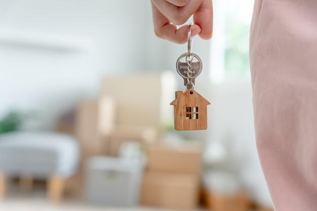 Verhuizing verhuizing Vrouw houdt de sleutelhanger van het huis in een nieuw appartement vast Verhuizing in een nieuw huis Koop of huur onroerend goed flat pacht erfpacht nieuwe verhuurder woning lening hypotheek
