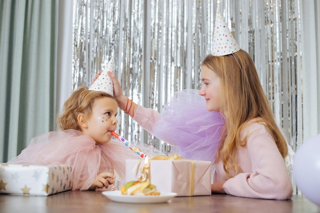 Verjaardag is vijf jaar oude oudere zus past zorgvuldig carnavalshoed aan van charmante jongere zus wh