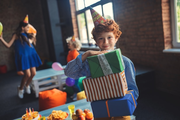 Verjaardag. Schattige roodharige jongen bedrijf presenteert en glimlachen