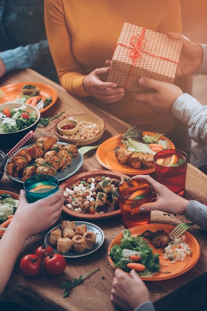 Verjaardagscadeau. Bovenaanzicht van een groep mensen die samen dineren terwijl de man een cadeaudoos geeft aan vrouwen