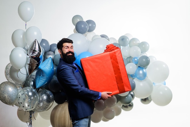Verjaardagscadeau gelukkige bebaarde man met heliumballonnen en grote geschenkdoos verjaardagsfeestje zakenman
