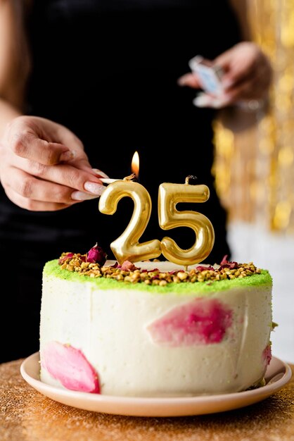 Foto verjaardagsfeest blanke vrouw in zwarte feestjurk die kaarsen aansteekt op verjaardagstaart