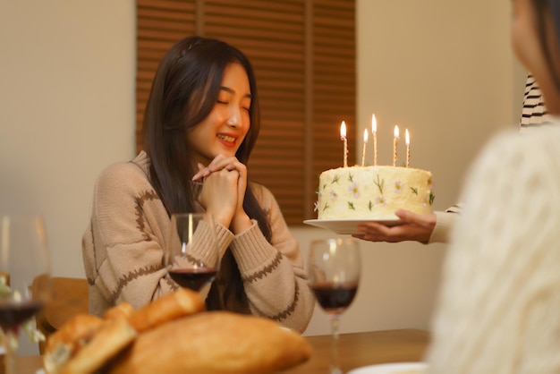 Verjaardagsfeestconcept Aziatische meisjes doen een wens terwijl ze een verjaardagstaart krijgen van een vriend op een feestje