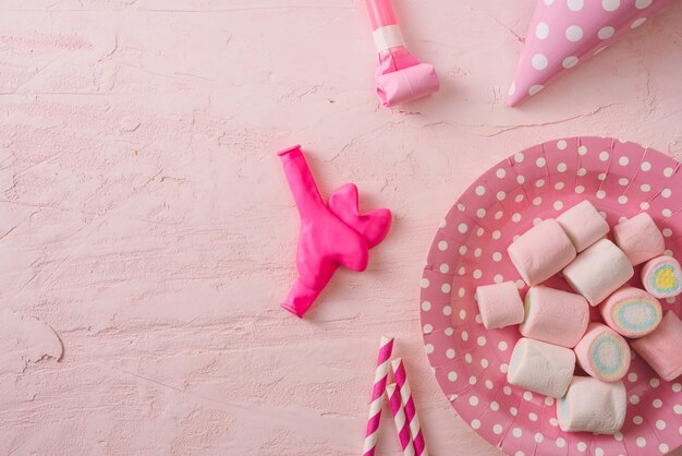 Verjaardagsfeestje achtergrond rand van confetti snoep lolly's en cadeau op roze oppervlakte kopie ruimte bovenaanzicht