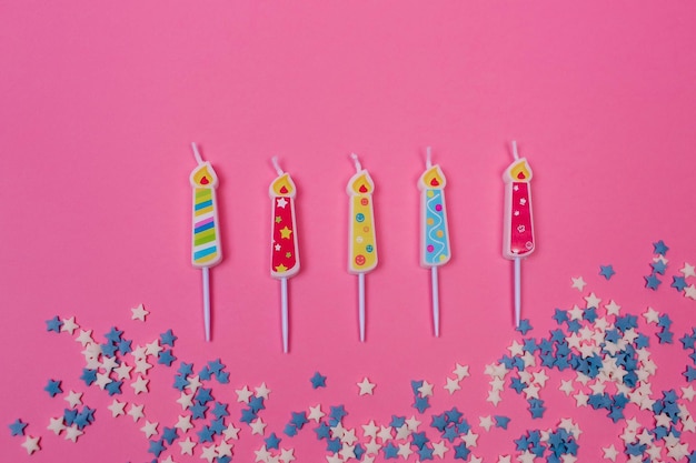 Verjaardagskaarsen en confetti op een roze achtergrond bovenaanzicht Platte lay-outsjabloon