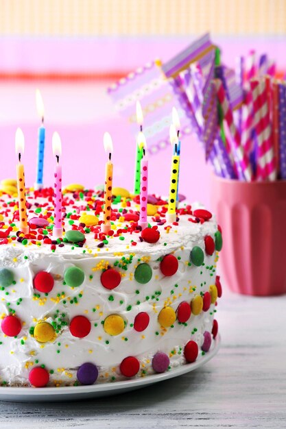 Verjaardagstaart met kaars op kleurrijke gestreepte achtergrond
