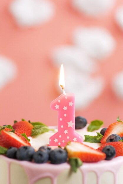 Verjaardagstaart nummer 1 Mooie roze kaars in cake op roze achtergrond met witte wolken Close-up en verticale weergave