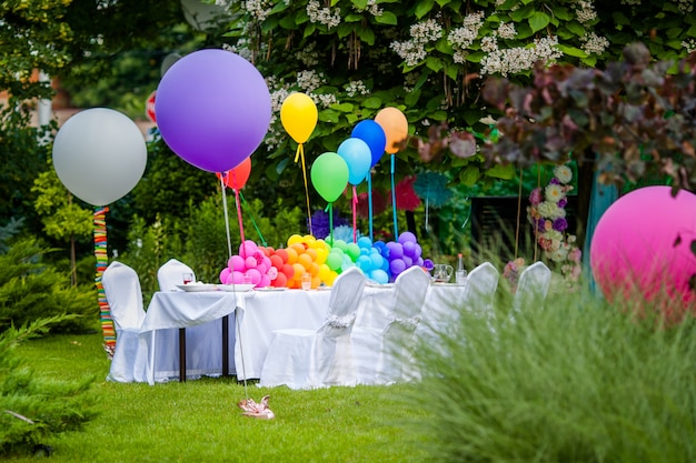 Verjaardagstafel met regenboogballonnen. Zomervakantie in het park.