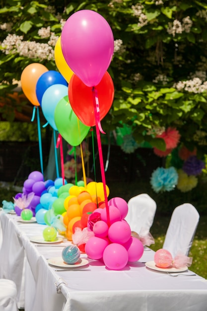 Verjaardagstafel met regenboogballonnen. Zomervakantie in het park.