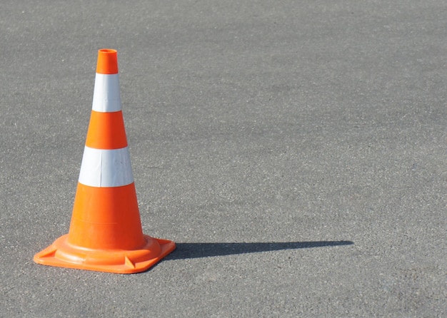 Verkeerskegel met witte en oranje strepen op grijze asfaltkopieerruimte Helder weer