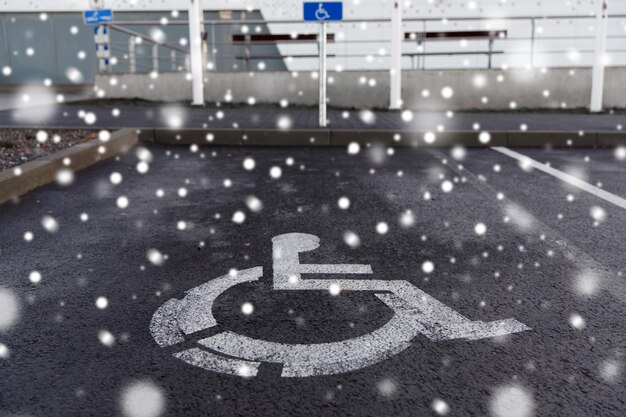 verkeerswetten en snelweg code concept - parkeerplaats verkeersbord voor gehandicapten buitenshuis over sneeuw