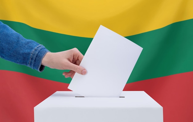 Verkiezingen in Litouwen Een hand gooit een stembiljet in de stembus De vlag van Litouwen