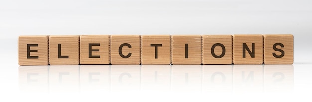Verkiezingen woord geschreven in houten kubussen op witte glanzende achtergrond met reflectie