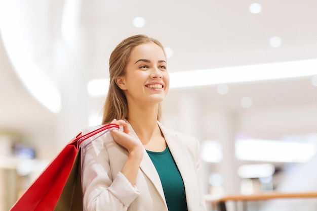 verkoop, consumentisme en mensenconcept - gelukkige jonge vrouw met boodschappentassen in winkelcentrum