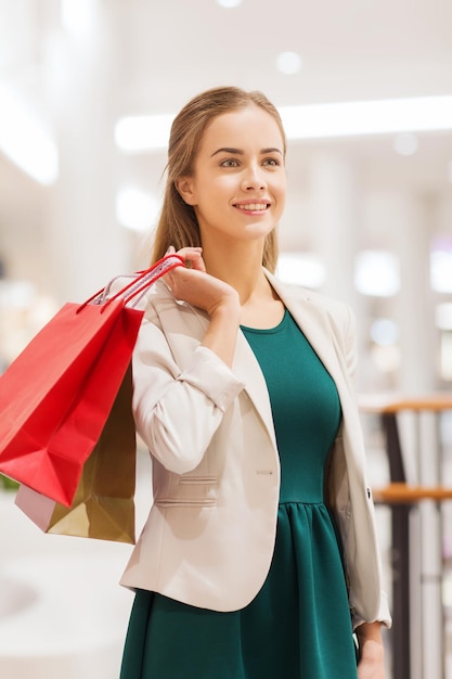 verkoop, consumentisme en mensenconcept - gelukkige jonge vrouw met boodschappentassen in winkelcentrum