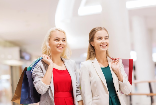 verkoop, consumentisme en mensenconcept - gelukkige jonge vrouwen met boodschappentassen in winkelcentrum