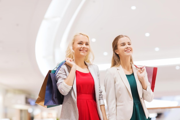 verkoop, consumentisme en mensenconcept - gelukkige jonge vrouwen met boodschappentassen in winkelcentrum