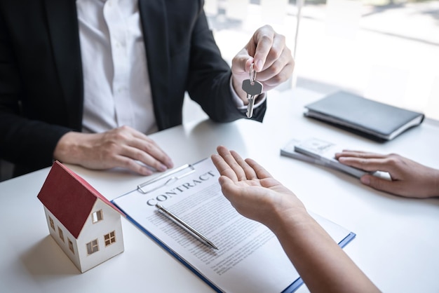 Verkoop koopcontract om een huis te kopen, makelaar presenteert woningkrediet en geeft sleutels aan klant na ondertekening contract om huis te kopen met goedgekeurd eigendomsaanvraagformulier.