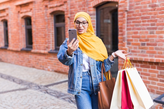 Verkoop, technologieën en koopconcept - gelukkige arabische moslimvrouw die daarna selfie buiten neemt