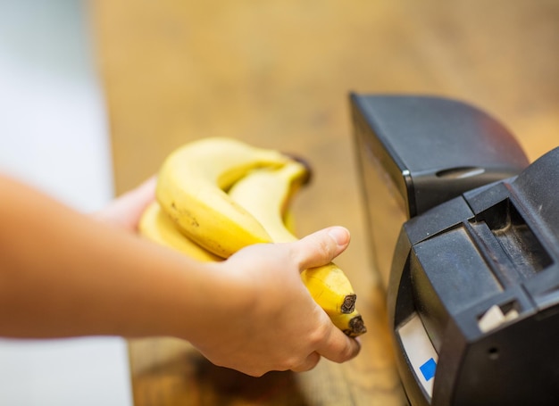 verkoop, winkelen, betalen, consumentisme en mensenconcept - close-up van handen die bananen kopen of scannen bij de kassa in de voedselmarkt of winkelcentrum