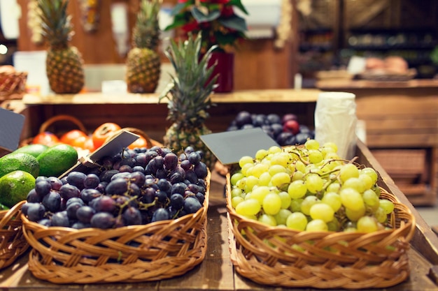 verkoop, winkelen en eco food concept - rijpe rode en witte druif in manden met naambordjes op de supermarkt