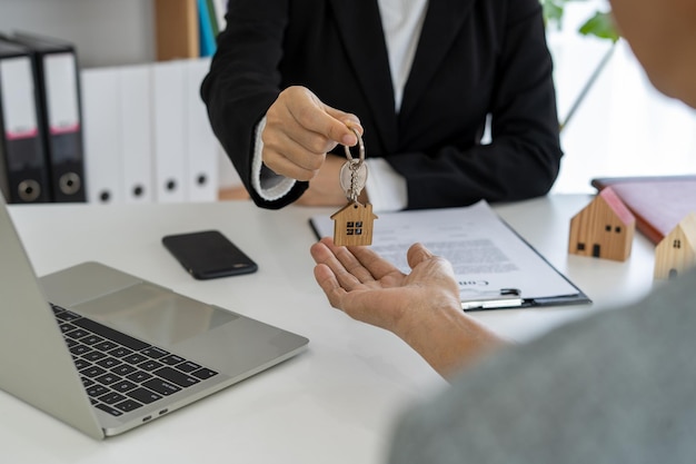 Verkoopagenten sturen huissleutels naar klanten na het bespreken van contracten om een woningverzekering of onroerendgoedlening te kopen