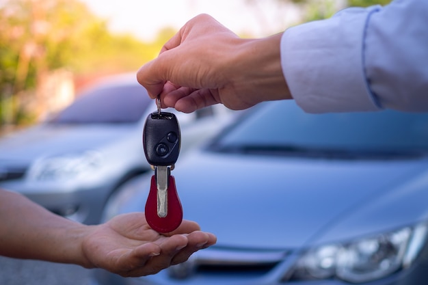 Verkoopmedewerkers sturen autosleutels naar toeristen na het maken van een lease. Huur of koop autoconcept