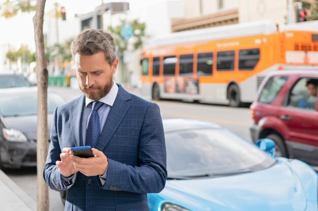 Verkoper chatten op mobiele telefoon rijke man huur auto kopieerruimte