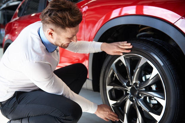 Verkoper die de glanzende velgen in nieuwe auto controleert