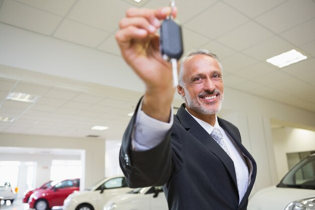 Foto verkoper die terwijl het aanbieden van autosleutels bevindt zich