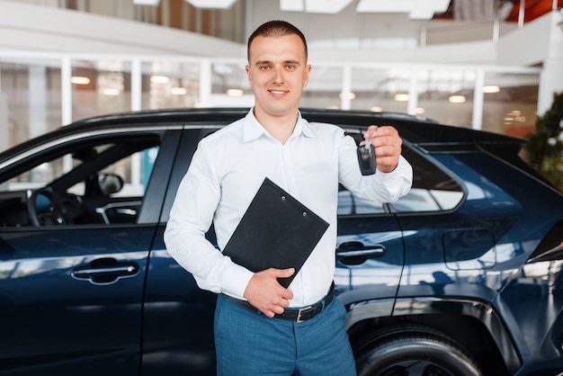 Verkoper geeft sleutel van nieuwe auto in showroom.