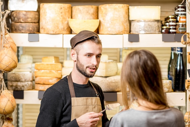 Verkoper met een vrouwelijke klant die een kaas kiest om in de levensmiddelenwinkel te kopen