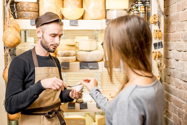 Verkoper met een vrouwelijke klant die een kaas kiest om in de levensmiddelenwinkel te kopen