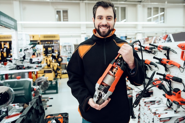 Verkoper poseert met schijfmolen in winkel voor elektrisch gereedschap.