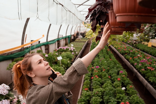 Verkoper van tuincentrum die klant telefonisch raadpleegt en plant in pot aanraakt