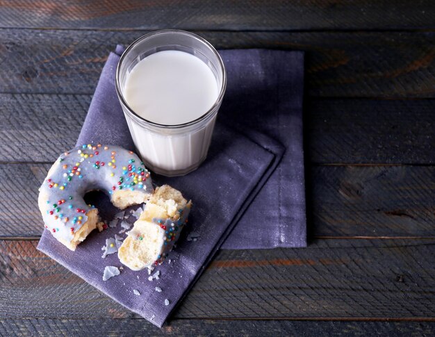 Foto verkruimelde donut op servet met glas melk op rustieke houten planken achtergrond