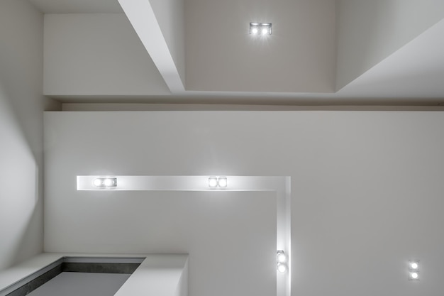 Verlaagd plafond met halogeenspots lampen en gipsplaten constructie in lege ruimte in appartement of huis Spanplafond wit en complexe vorm