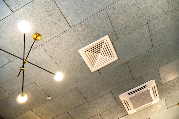 Verlaagd plafond met ventilatiegaten en lampen Interieurontwerp in een café of restaurant Geforceerde ventilatie in een muur onder het plafond