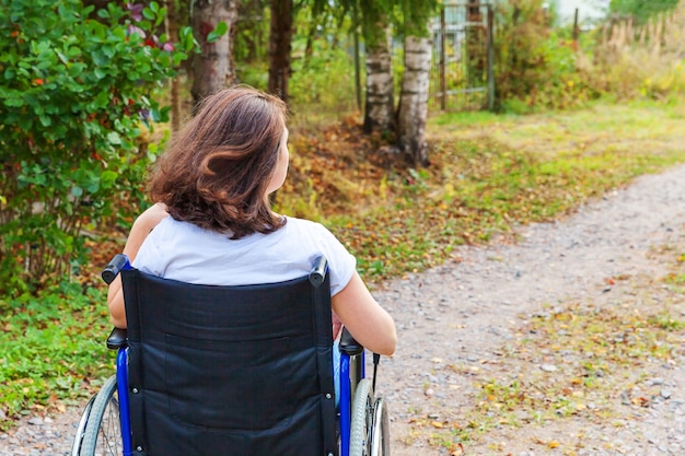 Verlamd meisje in ongeldige stoel voor mensen met een handicap buiten in de natuur