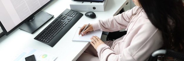 Verlamde vrouw in rolstoel met documenten gebruikt computer freelancer met documenten aan het doen