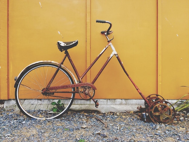 Foto verlaten fiets tegen een gele muur.