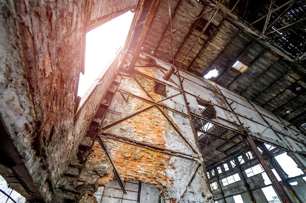 Verlaten industrieel interieur van de fabriek zonder ramen en veel gaten op de achtergrond van het plafond Oude verwoeste fabriek binnen