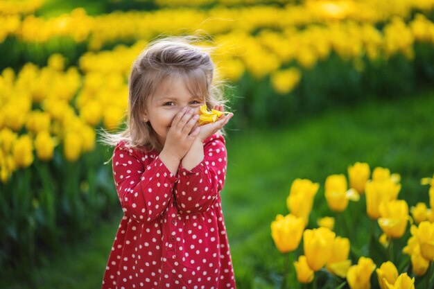 Verlegen gelukkig Oekraïens meisje op een bloeiend gazon van gele tulpen