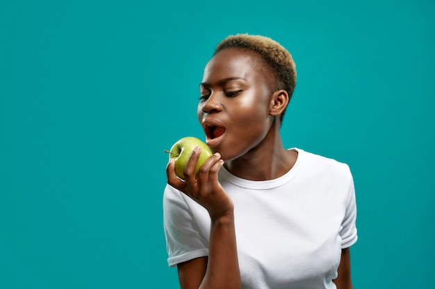 Verleidelijke Afrikaanse vrouw met groene appel en bijten.