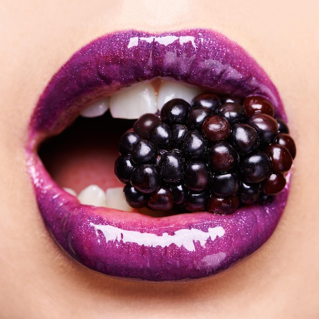Verleidelijke braambes Shot van een vrouw die paarse lippenstift draagt en in een braam bijt