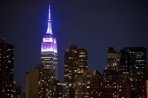 Verlicht empire state gebouw in de stad tegen een heldere hemel in de schemering